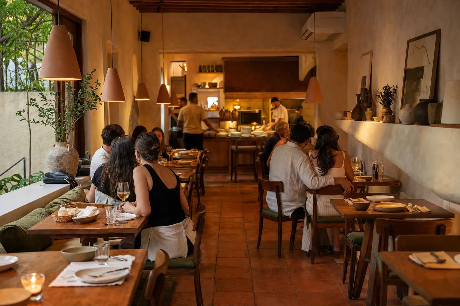 Salão intimista do restaurante com mesas de madeira e luz quente